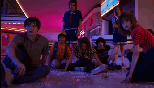 A Group Of People Are Sitting On The Floor In A Mall Looking At Something . GIF