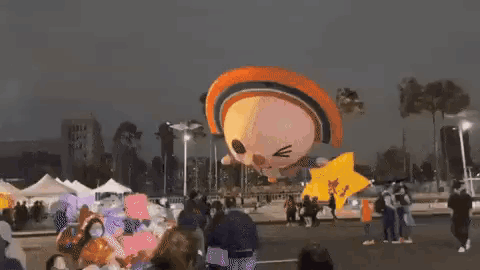 A Group Of People Are Standing Around A Balloon That Looks Like A Cat Flying In The Air . GIF