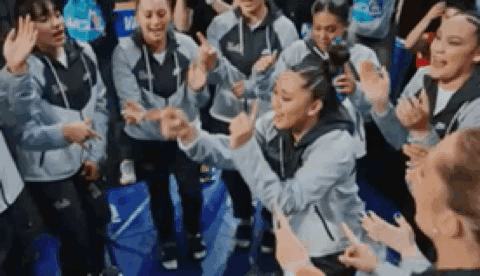 a group of people are standing around a basketball court giving high fives .