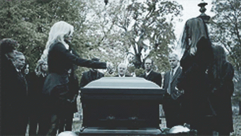 A Group Of People Are Standing Around A Coffin GIF