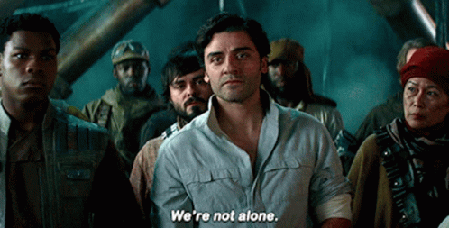 A Group Of People Are Standing Around A Man Who Says " We 'Re Not Alone " GIF