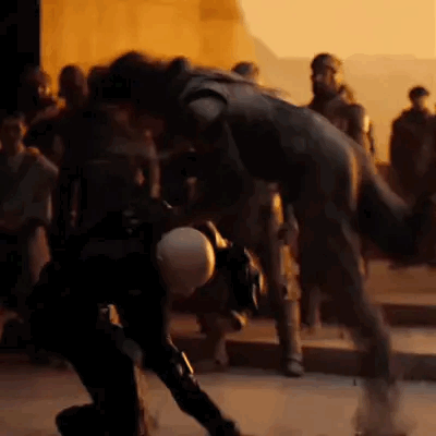 A Group Of People Are Standing Around A Statue Of A Man In A Black Suit . GIF
