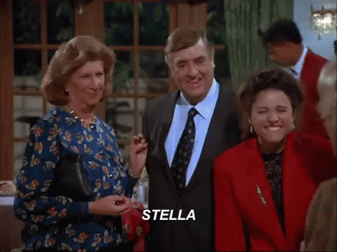 A Group Of People Are Standing Around A Table With The Word Stella Written On The Screen GIF