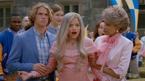A Group Of People Are Standing Around A Woman In A Pink Dress And A Man In A Blue Suit GIF