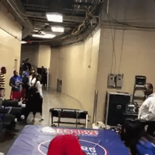 A Group Of People Are Standing Around A Wrestling Mat With A Red Hat On It That Says Boston GIF