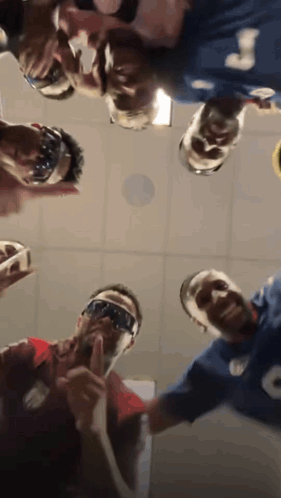 A Group Of People Are Standing In A Circle Looking Up At The Camera . GIF