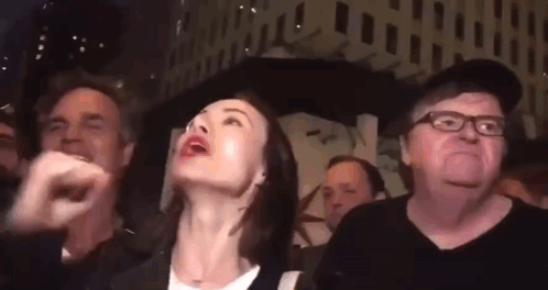 A Group Of People Are Standing In A Crowd And Looking Up At Something . GIF