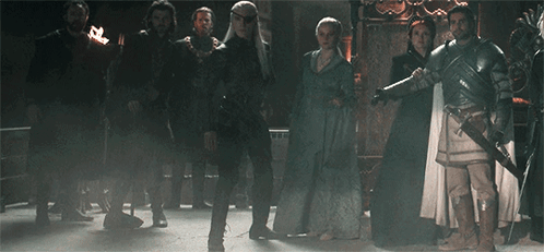 A Group Of People Are Standing In A Dark Room . GIF
