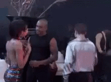 A Group Of People Are Standing In A Dark Room Talking To Each Other GIF