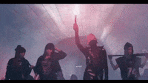 A Group Of People Are Standing In A Dark Room With A Man Holding A Red Flare . GIF