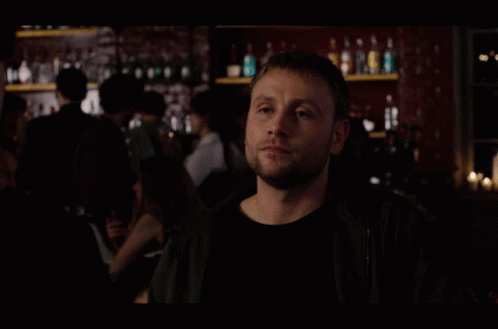 A Group Of People Are Standing In A Dark Room With A Man Looking Up GIF