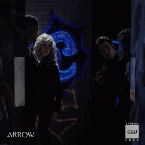 A Group Of People Are Standing In A Dark Room With Arrow Written On The Bottom GIF
