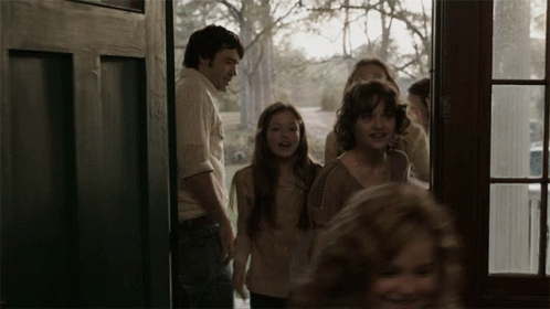 A Group Of People Are Standing In A Doorway Looking Out The Window GIF