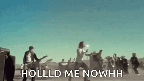 A Group Of People Are Standing In A Field Playing Guitars And Singing A Song . GIF