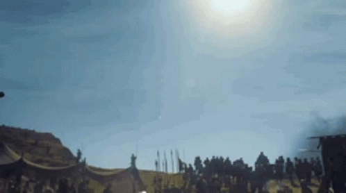 A Group Of People Are Standing In A Field With A Tent In The Background . GIF