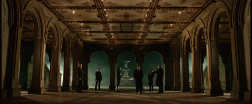 a group of people are standing in a hallway with arches
