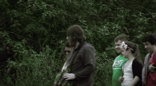 A Group Of People Are Standing In A Line And One Of Them Is Wearing A Shirt That Says ' Abercrombie ' On It GIF