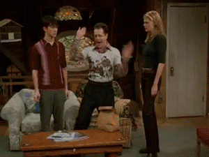 a group of people are standing in a living room and one of them is wearing a shirt that says ' i love you '