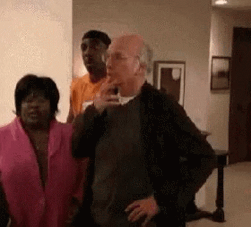 A Group Of People Are Standing In A Living Room . One Of The People Is Smoking A Cigarette . GIF