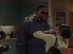 A Group Of People Are Standing In A Living Room Talking To Each Other . GIF