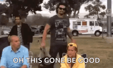 A Group Of People Are Standing In A Park And One Of Them Is Holding A Bag . GIF