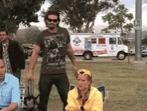 A Group Of People Are Standing In A Park In Front Of A Pizza Truck GIF