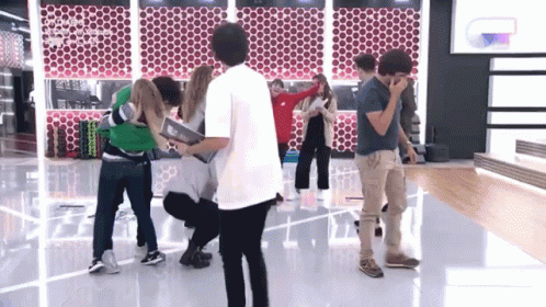 A Group Of People Are Standing In A Room And One Of Them Is Wearing A Shirt That Says ' Coco ' On The Back GIF