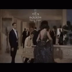 a group of people are standing in a room with a chandelier .