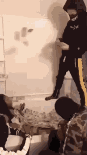 A Group Of People Are Standing In A Room With A Man In A Black Hoodie Standing In The Middle Of The Room . GIF