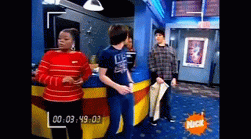 A Group Of People Are Standing In A Room With A Nick Logo On The Wall . GIF