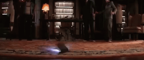 A Group Of People Are Standing In A Room With A Projector On The Floor . GIF