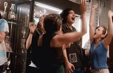 A Group Of People Are Standing In A Room With Their Arms In The Air And Screaming . GIF