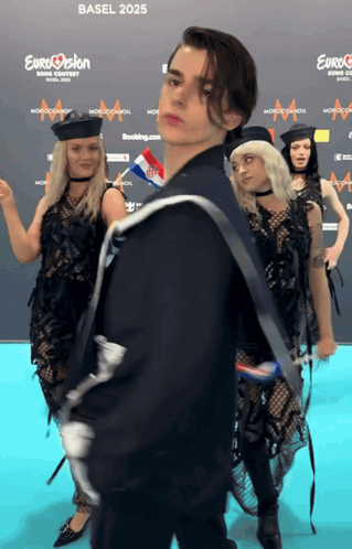 A Group Of People Are Standing In Front Of A Blue Carpet That Says Eurovision On It GIF