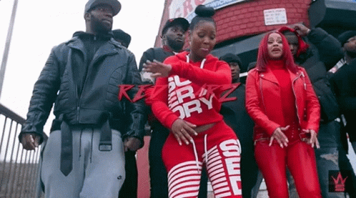 A Group Of People Are Standing In Front Of A Building Wearing Red Clothes . GIF
