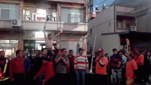 A Group Of People Are Standing In Front Of A Building With Chinese Writing On The Side GIF