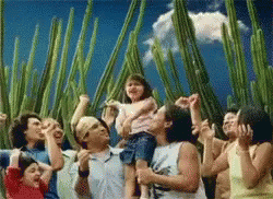 A Group Of People Are Standing In Front Of A Cactus Plant GIF