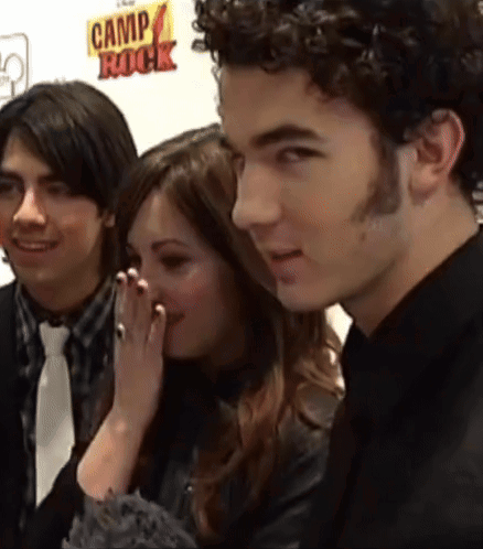 A Group Of People Are Standing In Front Of A Camp Rock Sign GIF