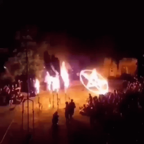 A Group Of People Are Standing In Front Of A Car That Is Burning . GIF