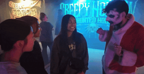 A Group Of People Are Standing In Front Of A Creepy House Sign GIF