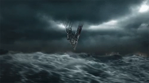 a group of people are standing in front of a large wave in the ocean at night .