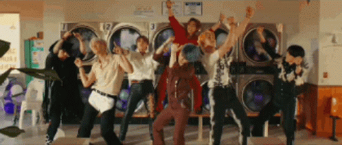 A Group Of People Are Standing In Front Of A Laundromat . GIF