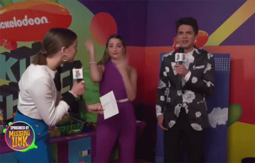 A Group Of People Are Standing In Front Of A Nickelodeon Logo GIF