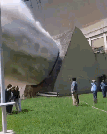A Group Of People Are Standing In Front Of A Pyramid In A Park . GIF