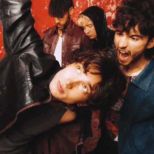 A Group Of People Are Standing In Front Of A Red Wall GIF