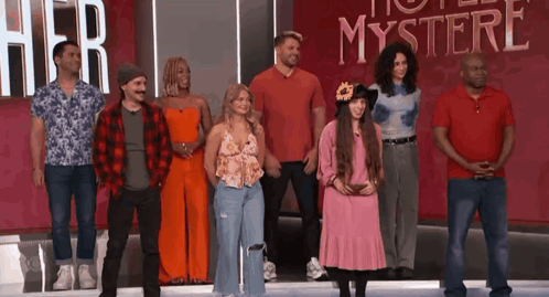a group of people are standing in front of a sign that says " her mystery "