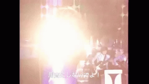 A Group Of People Are Standing In Front Of A Stage With A Huge Light Coming Out Of It . GIF