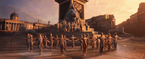 A Group Of People Are Standing In Front Of A Statue Of A Lion GIF