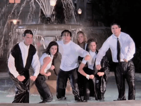 A Group Of People Are Standing In Front Of A Water Fountain GIF
