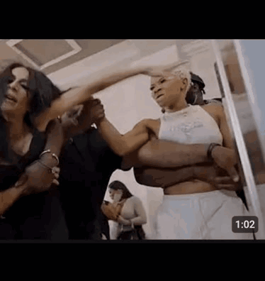 A Group Of People Are Standing Next To Each Other In A Room And Fighting . GIF