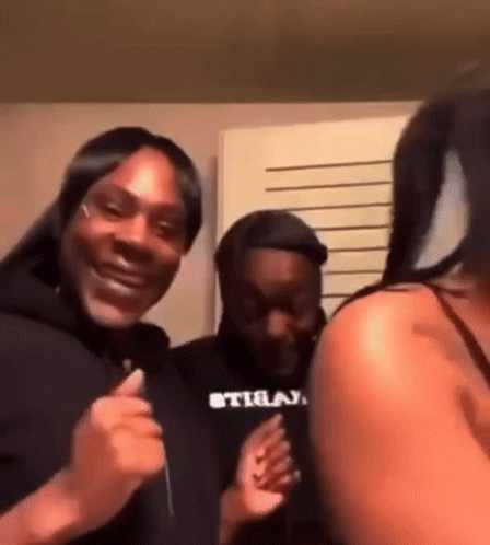 A Group Of People Are Standing Next To Each Other In A Room And Laughing . GIF